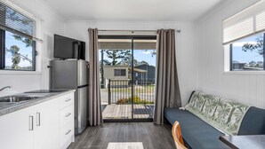 A compact kitchen with a built-in fridge, a dining area with a table and chairs, and a balcony with a view of the outside. - Crows Nest Tourist Park (Crows Nest)