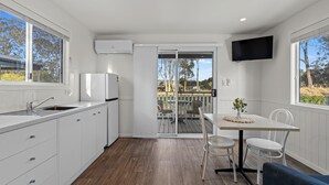 A modern kitchen with white cabinets, a built-in sink, and a large window. - Crows Nest Tourist Park (Crows Nest)