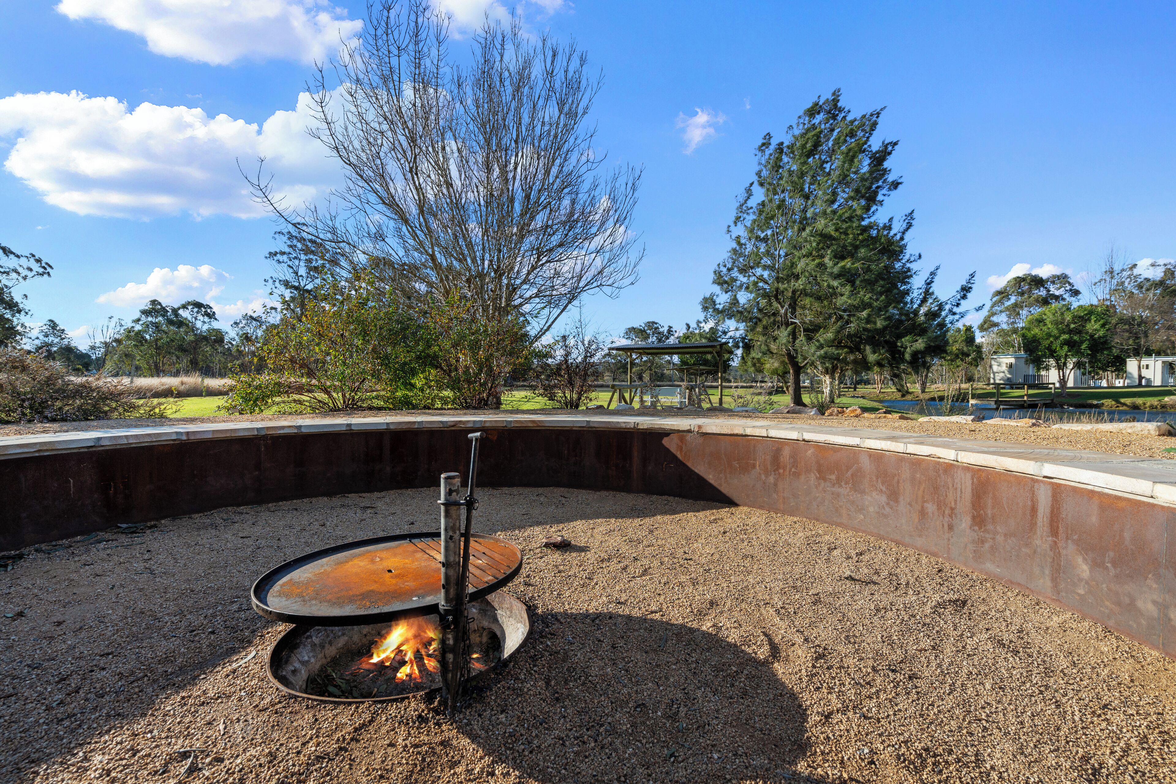 A circular outdoor seating area with a fire pit, surrounded by gravel and concrete.