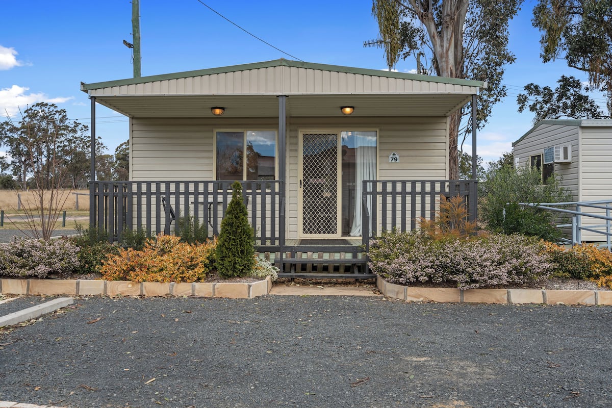 A small, single-story building with a porch and a fenced area.