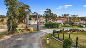 A residential area with a sign reading "Welcome to Crows Nest" and a well-maintained lawn with trimmed hedges and a mailbox. - Crows Nest Tourist Park (Crows Nest)