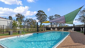 A rectangular swimming pool with clear blue water, surrounded by a gravel area and a fence. - Crows Nest Tourist Park (Crows Nest)