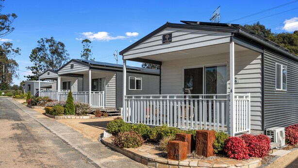 A row of single-story mobile homes with white railings and a small porch area. - Crows Nest Tourist Park (Crows Nest)