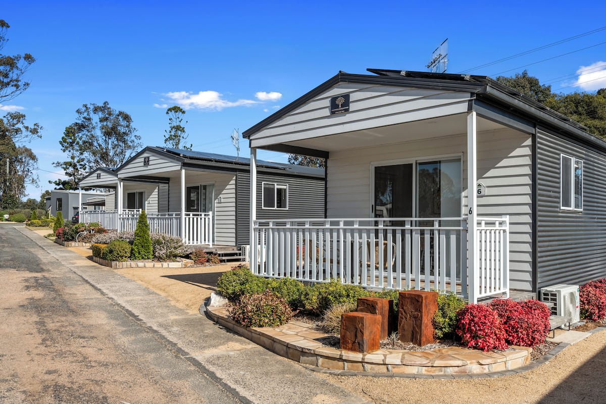 A row of single-story mobile homes with white railings and a small porch area.