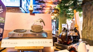 Un coin dédié à la préparation du thé, avec une théière et une bouilloire posées sur une table, entourées de tasses et de soucoupes.