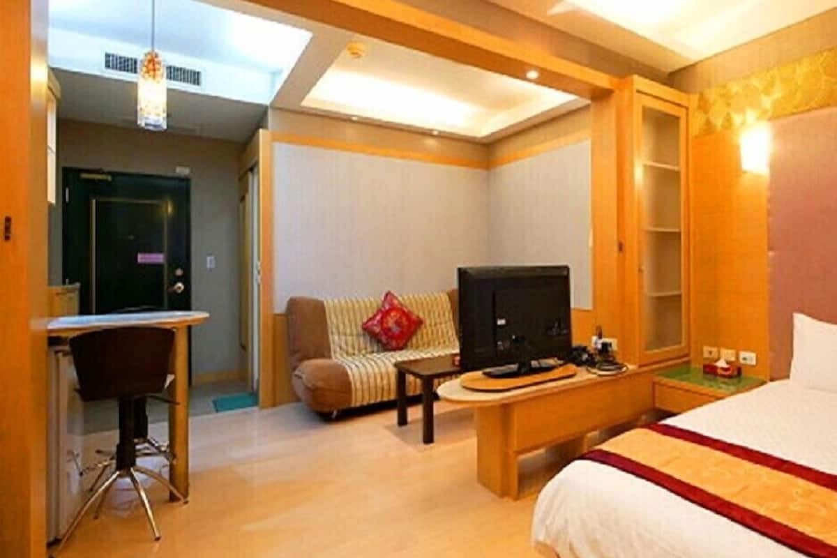 A hotel room with a bed, desk, television, and a sofa.