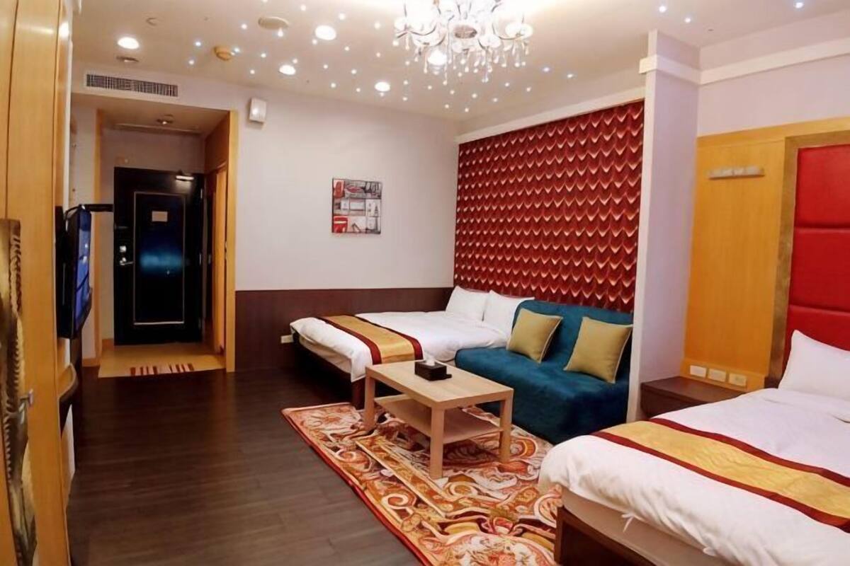A hotel room with a bed, sofa, and a television.