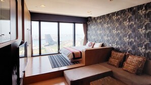 A modern hotel room with a large bed, a sofa, a TV, and a city view. - 85 Prague Homestay (Kaohsiung)