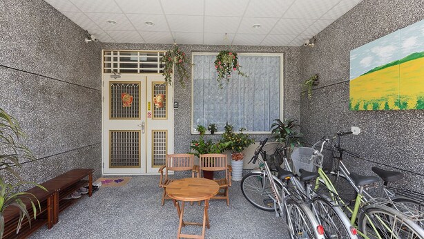 A room with a wooden table and chairs, a potted plant, a bicycle, and a door with a window. - Mei Di Ya Ju Guest House (Yuli)