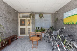 A room with a wooden table and chairs, a potted plant, a bicycle, and a door with a window. - Mei Di Ya Ju Guest House (Yuli)
