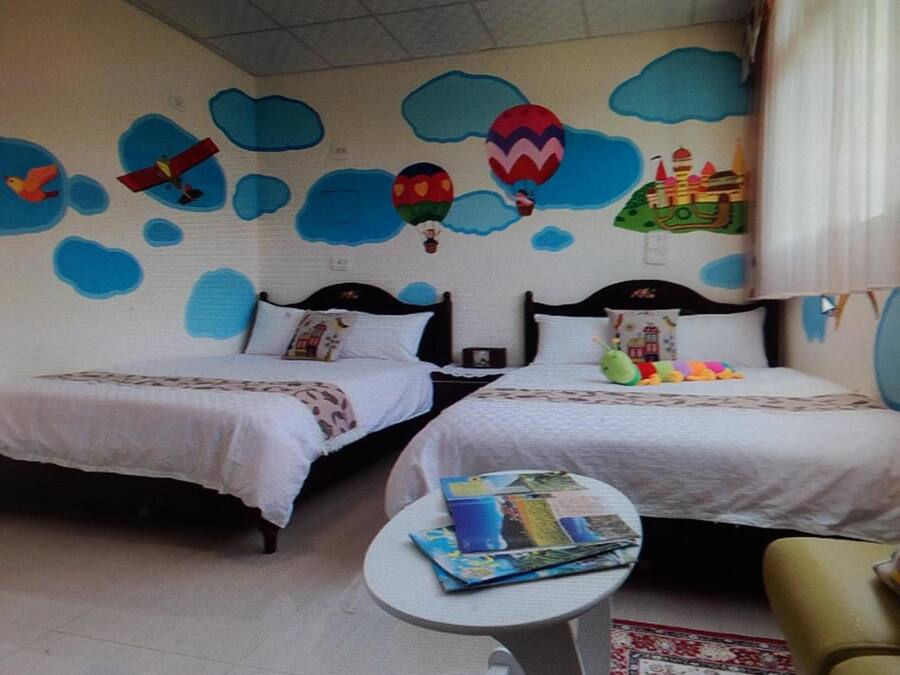 A room with two beds, a small table, and a chair.