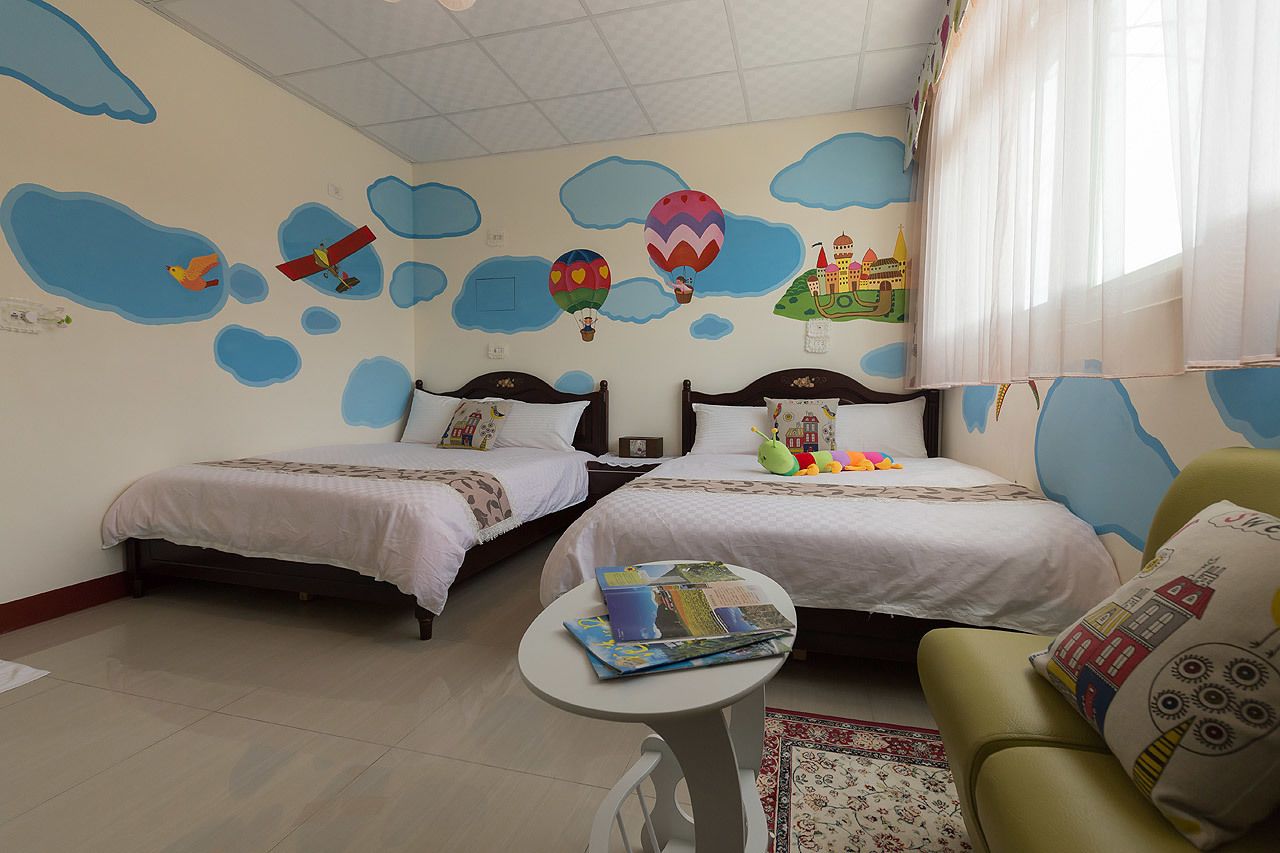 Una habitación con dos camas, una mesita pequeña y una silla verde.