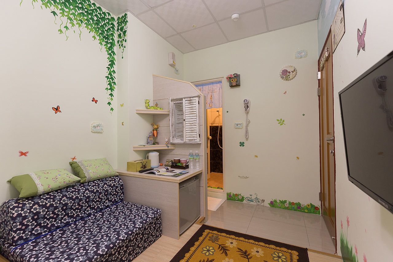 A small, cozy room with a bed, a desk, and a shower area.