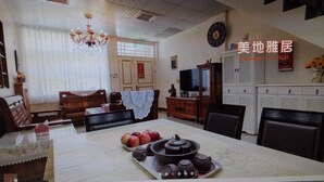 A traditional room with a wooden sofa, a dining table with a tea set, and a television. - Mei Di Ya Ju Guest House (Yuli)