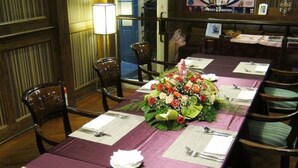 A dining area with a long table set for a meal, chairs around it, and a floral centerpiece. - Rhineinn Hotel (Keelung)