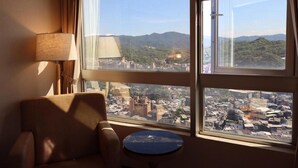 A hotel room with a large window offering a view of a cityscape and mountains. - Rhineinn Hotel (Keelung)