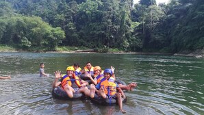 People on a raft in a river surrounded by dense greenery. - Harry & Mimin Homestay (Gorontalo)