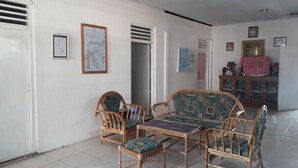A room with a dining table and four chairs, a cabinet with glass doors, and a door leading to another room. - Harry & Mimin Homestay (Gorontalo)