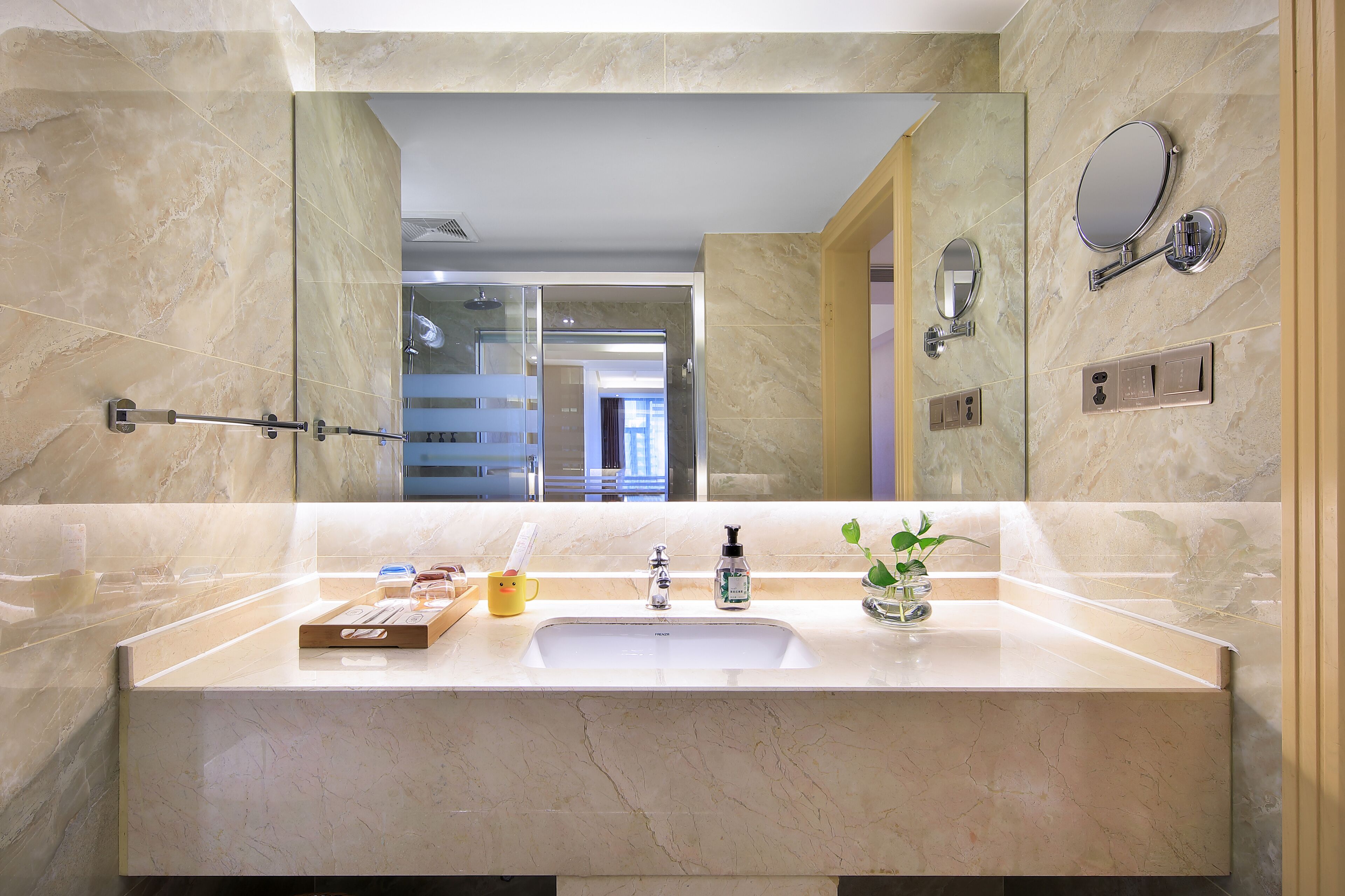 A bathroom with a large mirror, a sink with a soap dispenser, and a towel rack.