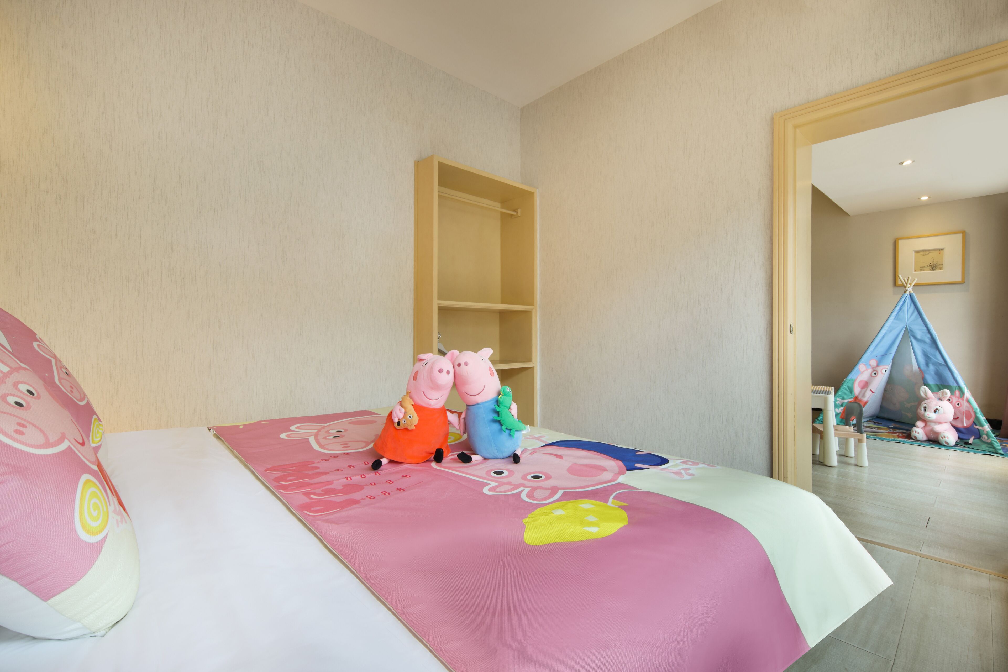 Un dormitorio infantil con una cama, un edredón rosa y blanco, y dos peluches sobre la cama.