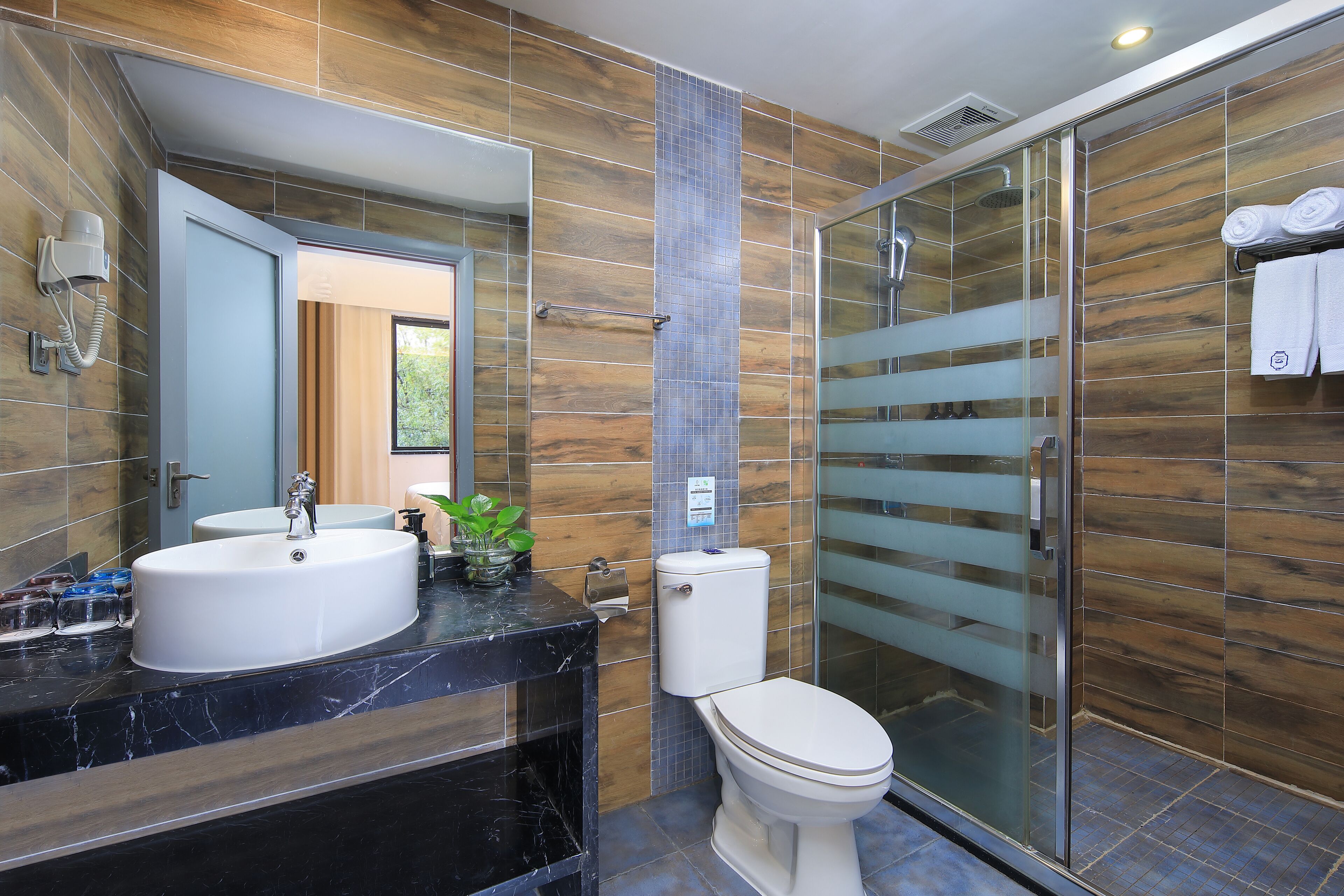 A modern bathroom with a large mirror, a sink, a toilet, and a shower area.