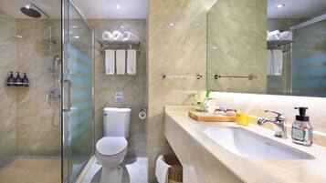 Une salle de bain moderne avec une douche à parois de verre, des toilettes, un lavabo équipé de produits de toilette et un miroir.