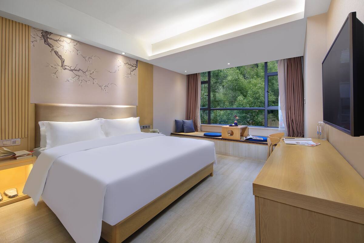 A modern hotel room with a large bed, a desk, and a TV.