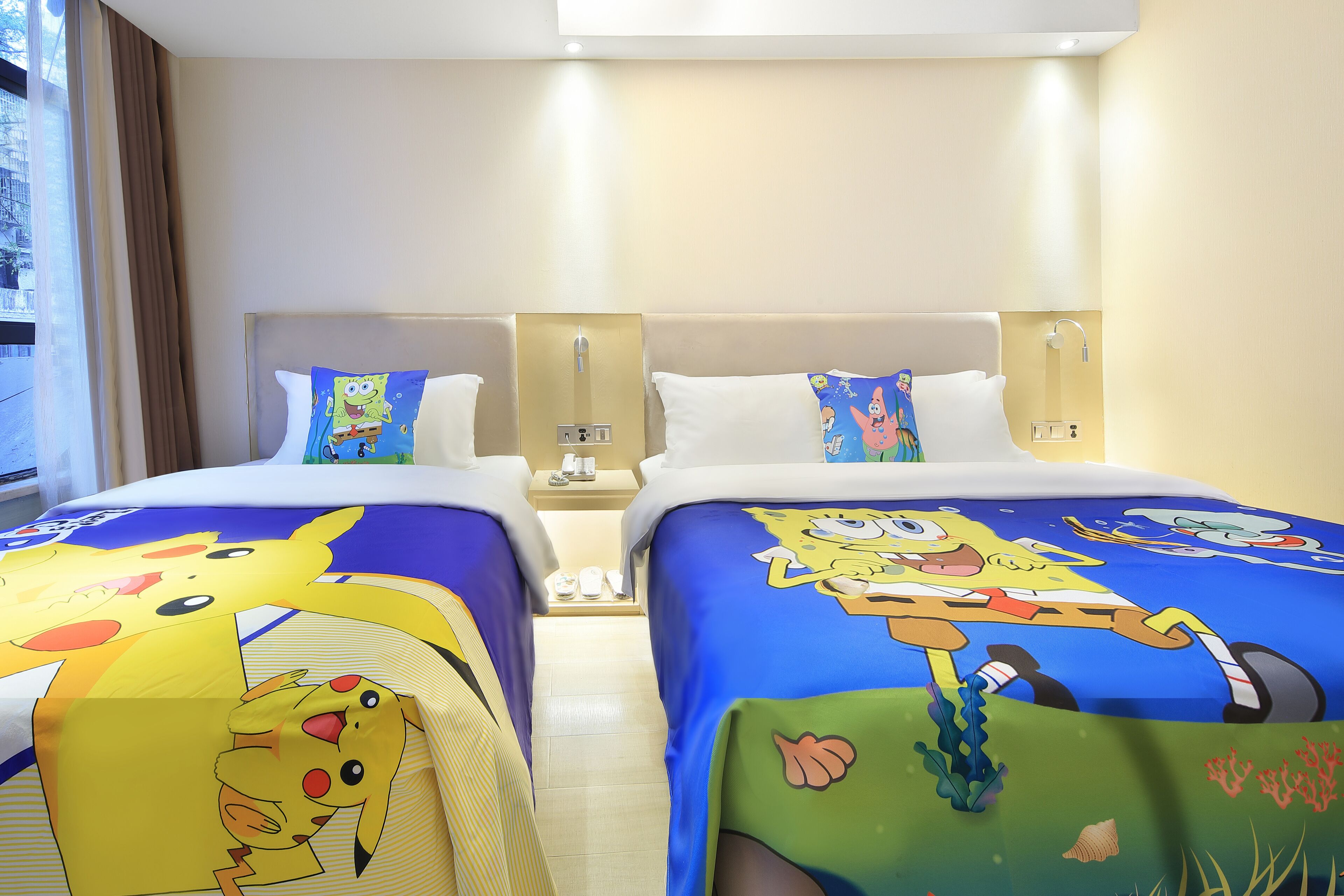 A hotel room with two beds, each covered with a themed bedspread featuring popular cartoon characters.