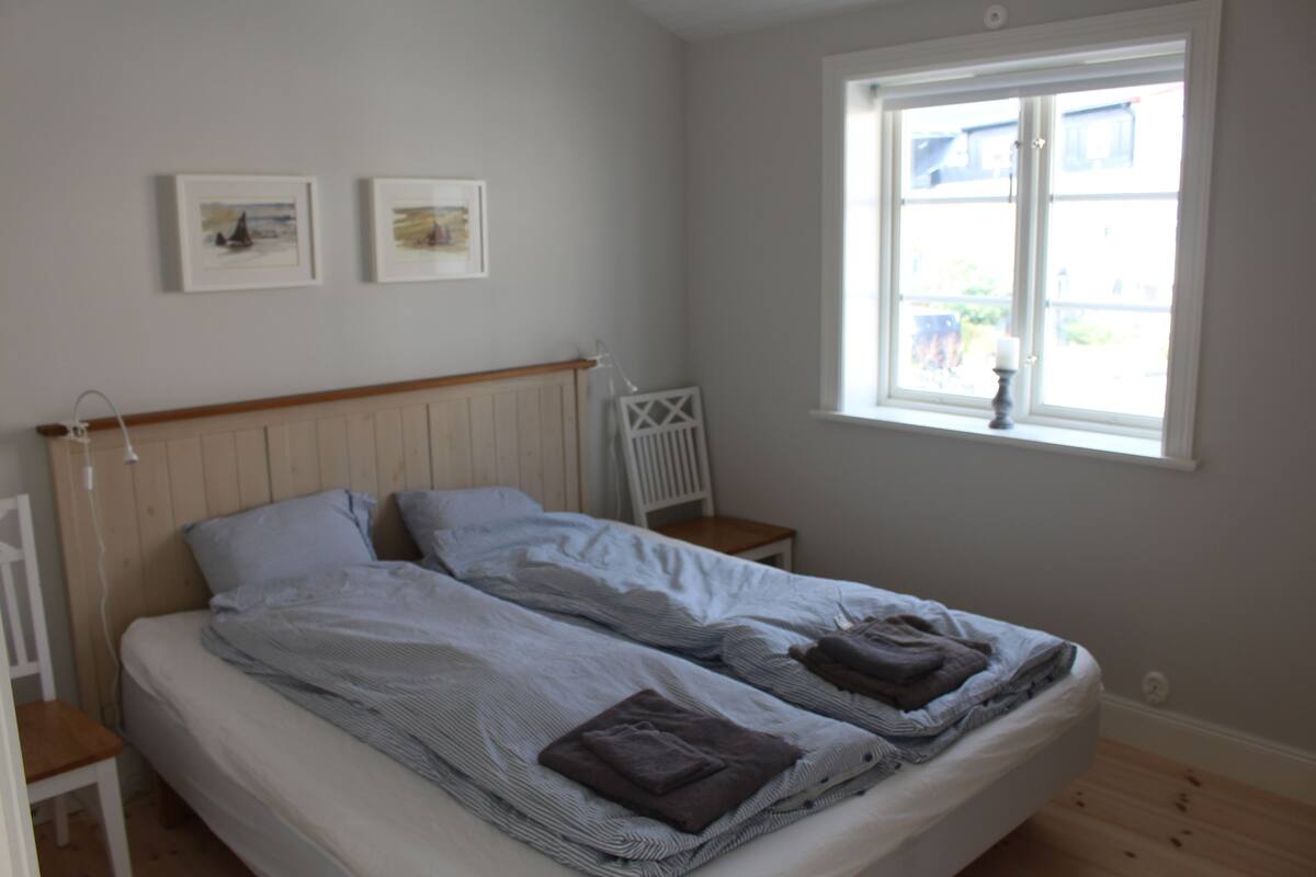 Une chambre avec deux lits, une fenêtre donnant sur un beau paysage et deux tableaux encadrés accrochés au mur.