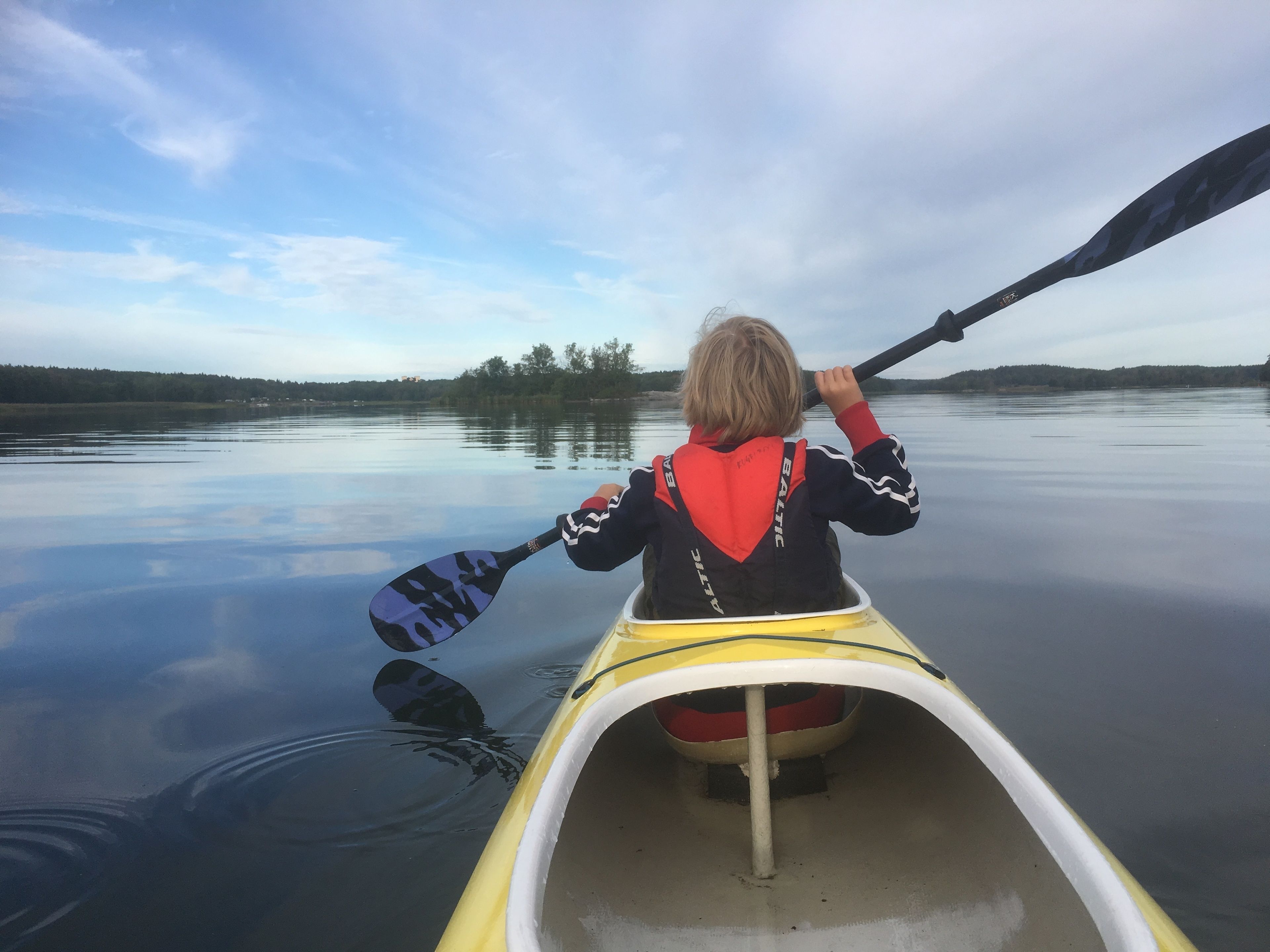 A person in a yellow kayak on calm water.