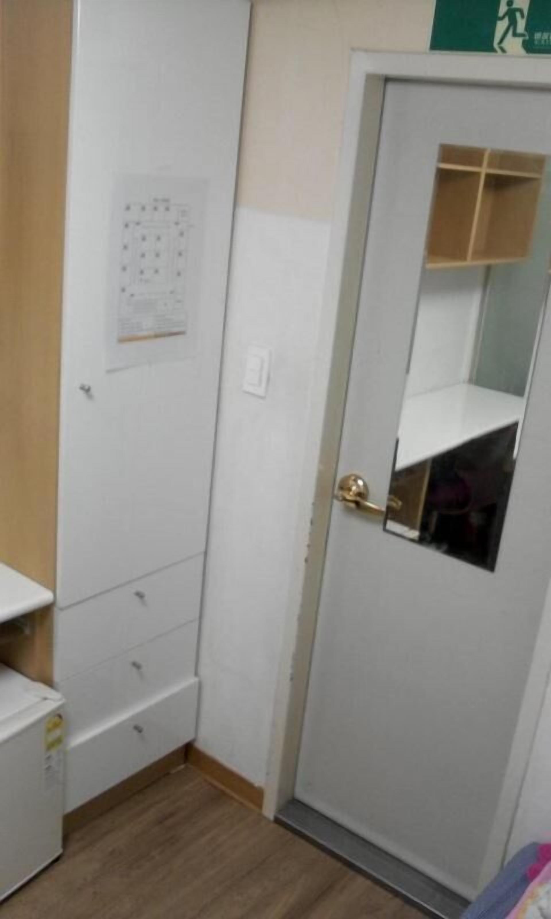 Ein kleiner Raum mit einem weißen Kleiderschrank, einer Tür mit Spiegel und einem Kalender an der Wand.
