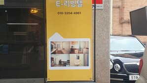 Un panneau jaune de LivingTel avec un numéro de téléphone et une petite image illustrant l’agencement d’une pièce.