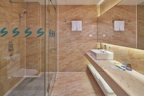A modern bathroom with a glass-enclosed shower, marble walls, a sink, and two towels hanging on hooks. - Sucha Hotel Chengdu Ligong Station (Chengdu)