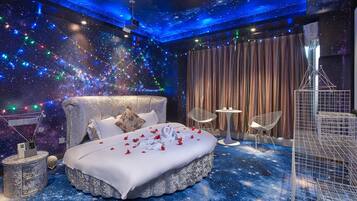 A bedroom with a bed, a nightstand, a chair, and a small table.