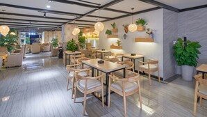 A modern restaurant with wooden tables and chairs, hanging pendant lights, and potted plants. - Sucha Hotel Chengdu Ligong Station (Chengdu)