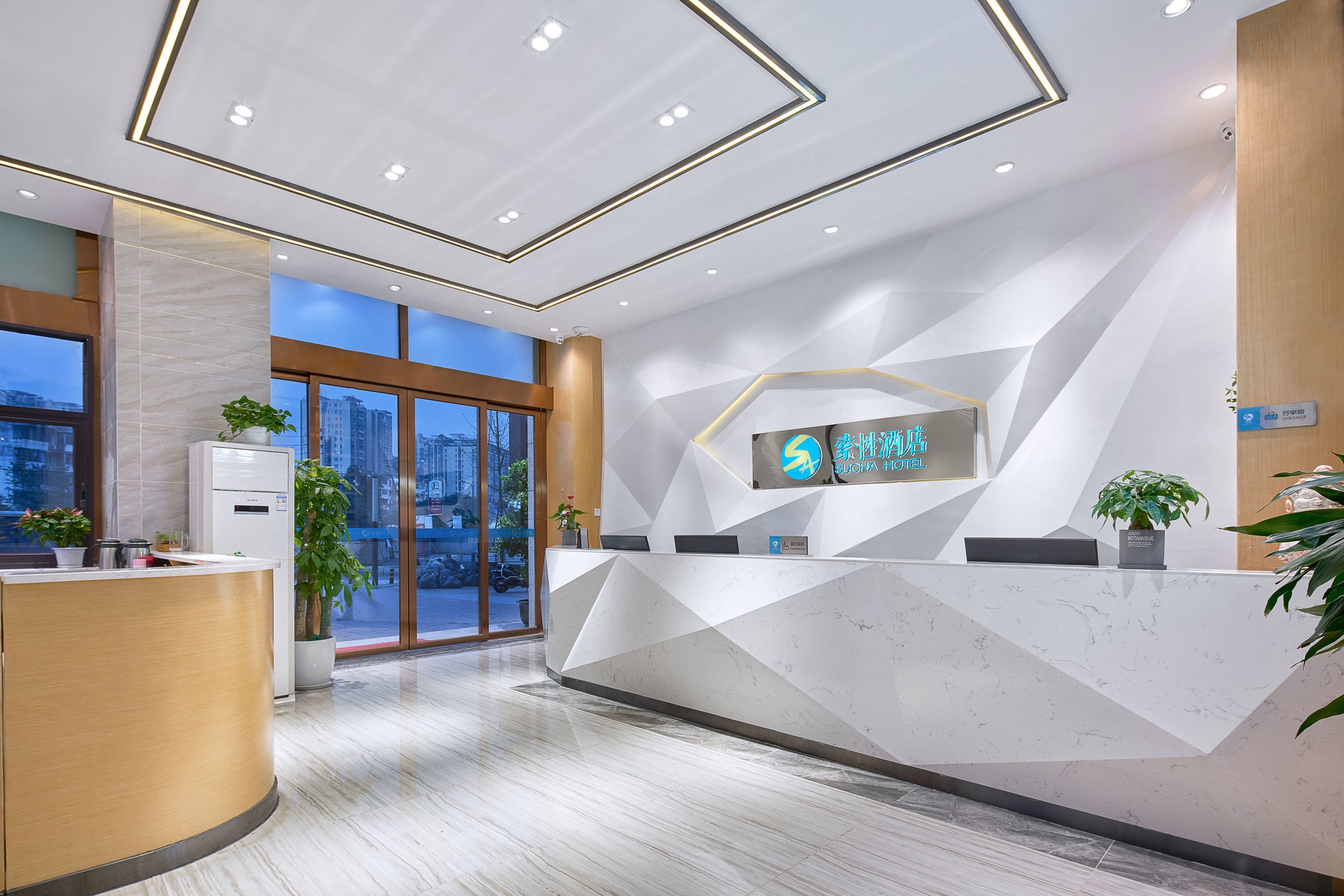 A modern hotel reception area with a geometric design, a reception desk, and a large window offering a city view.