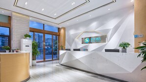 A modern hotel reception area with a geometric design, a reception desk, and a large window offering a city view. - Sucha Hotel Chengdu Ligong Station (Chengdu)