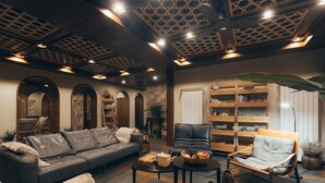 A cozy living room with a sofa, armchairs, a coffee table, and a bookshelf. - Floral Hotel Wuxi Qietintfengyin Resort (Wuxi)