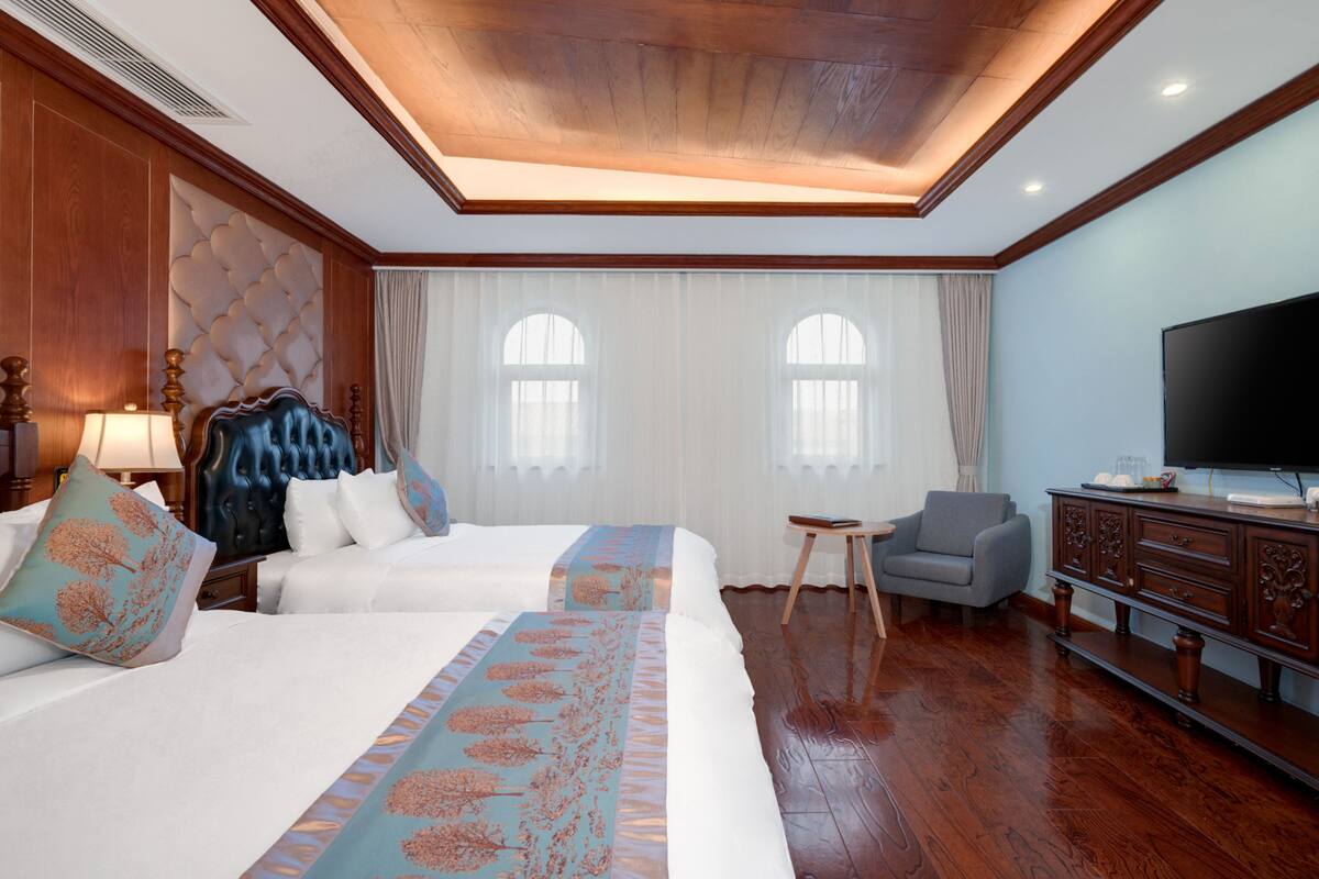 Une chambre d’hôtel avec deux lits, une télévision, une petite table et un placard.