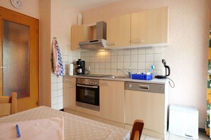 Una cocina con armarios de madera, estufa, lavavajillas y cafetera.