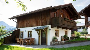 Eine Holzhütte mit einem Balkon, einem Essbereich mit Stühlen und Topfpflanzen.