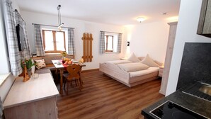 Ein gemütliches Zimmer mit Holzboden, einem Bett, einer Essecke mit Tisch und Stühlen sowie einer Küchenzeile mit Herd.