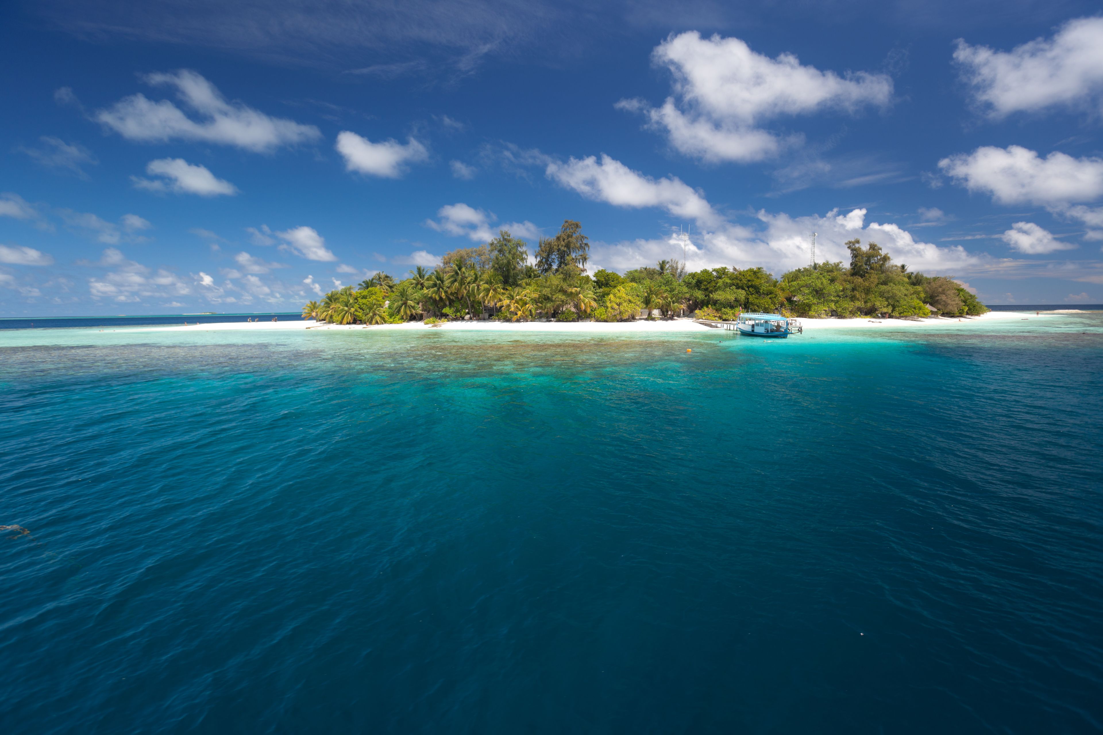 Uma ilha tropical com águas turquesa cristalinas, vegetação exuberante e um pequeno barco.