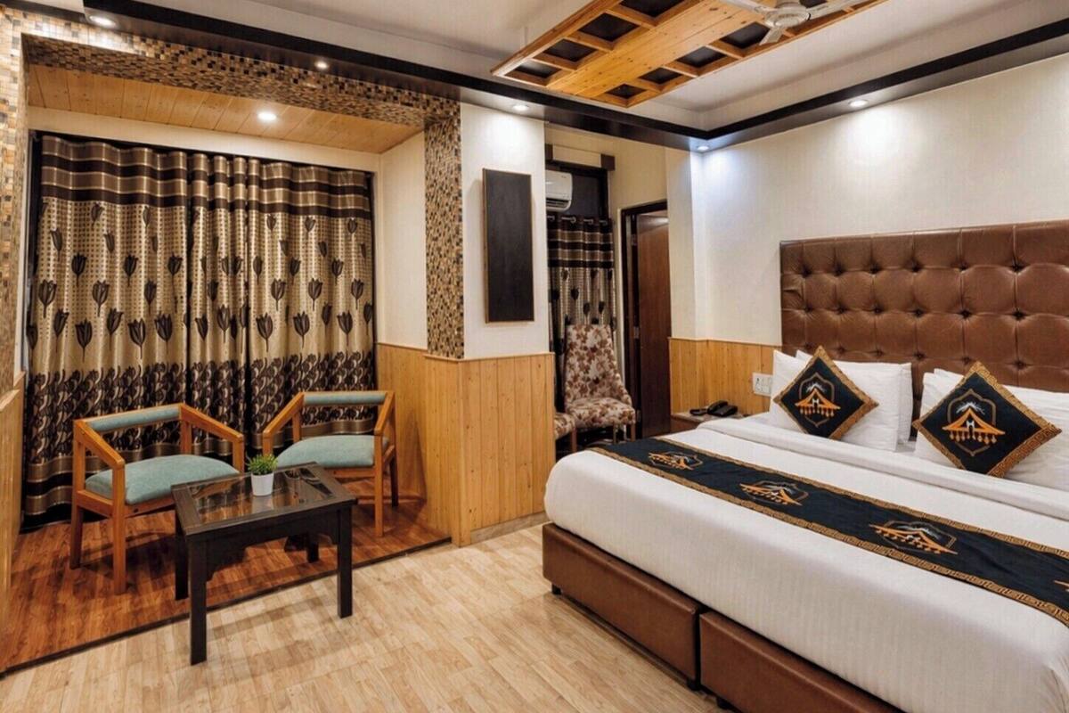 A hotel room with a bed, two chairs, a small table, and a decorative curtain.