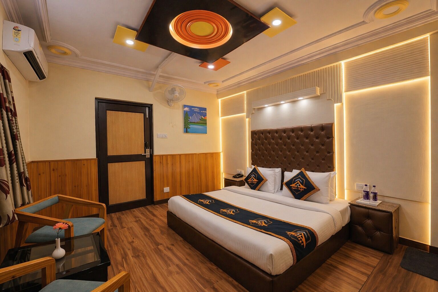 Een hotelkamer met een bed, een stoel, een nachtkastje en een ingebouwde airconditioner.