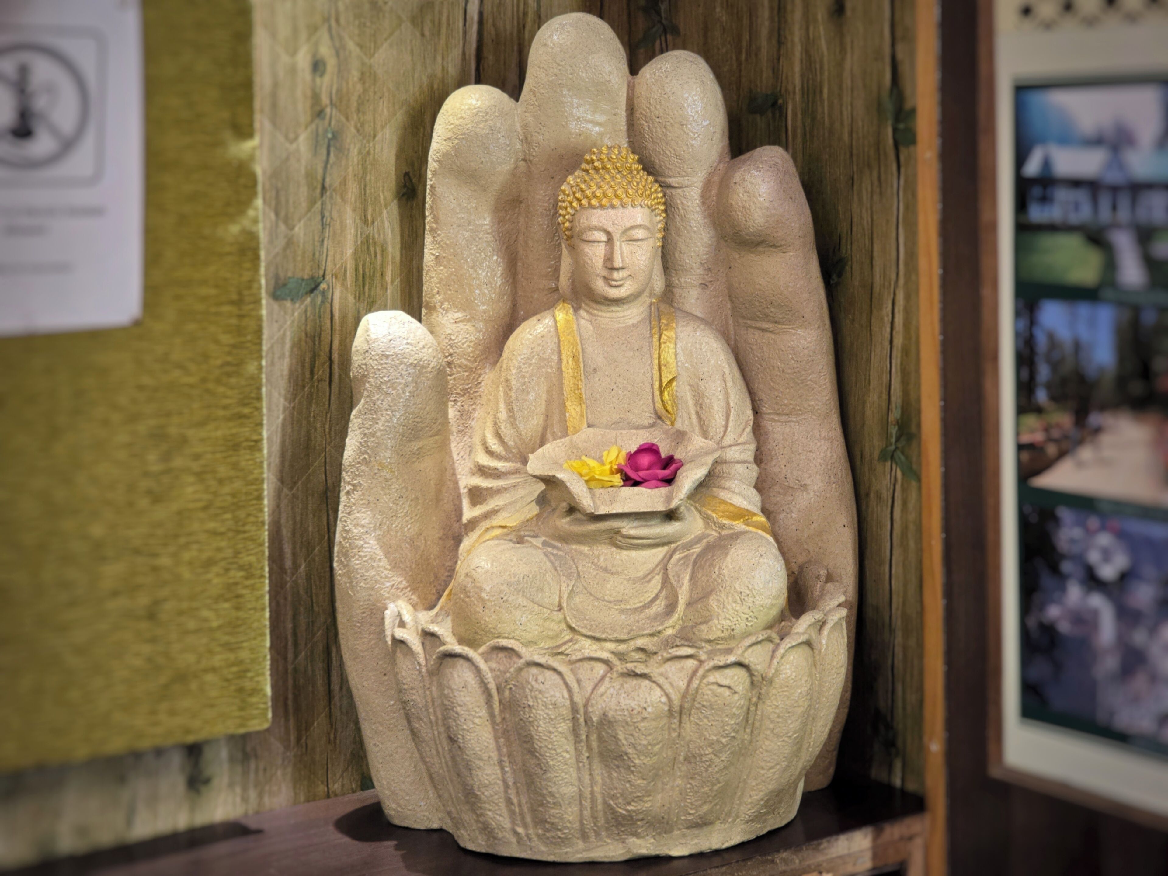 Estátua de uma figura sentada em posição de lótus, com uma tigela de flores.