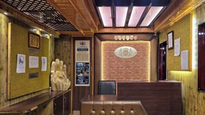 A reception area with a wooden interior, a reception desk, a seating area, and a Buddha statue.