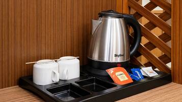 A stainless steel kettle, two white mugs, and tea packets on a tray.