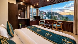 A hotel room with a bed, a desk, a TV, and a view of a cityscape.
