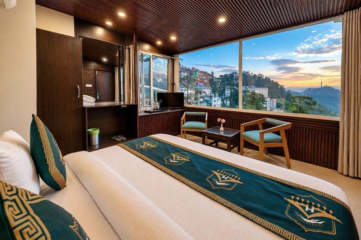 A hotel room with a bed, a desk, a TV, and a view of a cityscape.